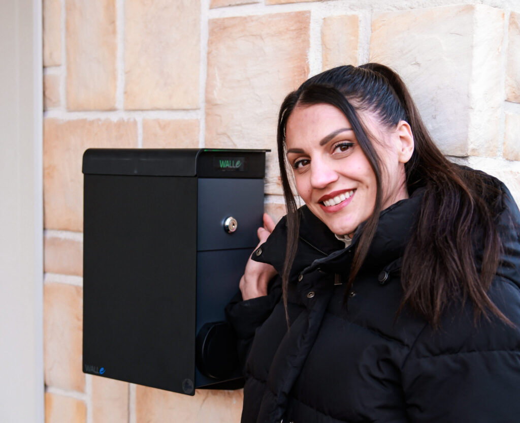 Aitajuoksija Nooralotta Neziri ja musta sähköauton laturi TuplaWalle omakotiltalon pihalla